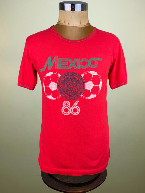 Red t-shirt with 'Mexico 86' graphic on a mannequin against a beige background
