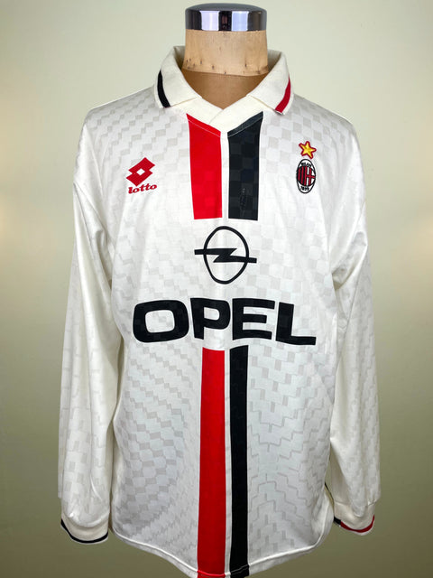 A vintage long-sleeve AC Milan soccer jersey by Lotto, featuring a white base with red and black vertical stripes, the Opel logo, and the AC Milan crest, displayed on a wooden mannequin torso.