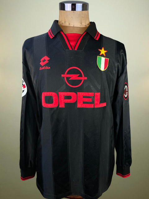 Black AC Milan jersey made by Lotto with red Opel Sponsor in flock and logos on a mannequin against a neutral background