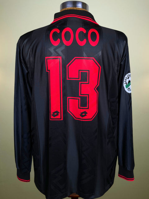 Black AC Milan 1996 Third jersey with red text 'COCO' and number '13' on a beige background