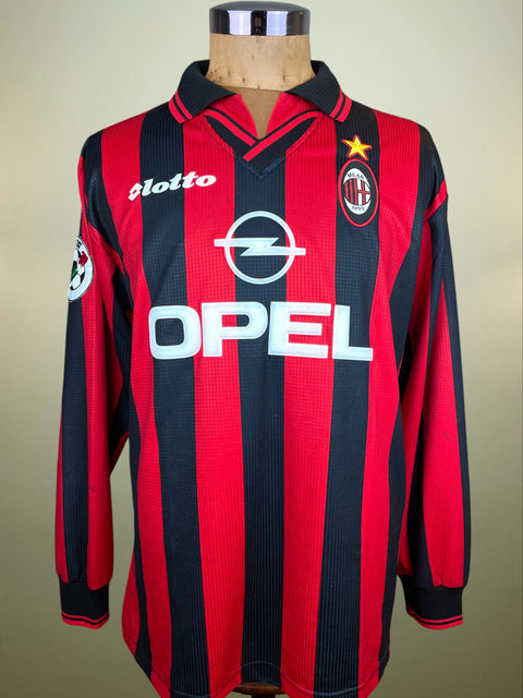 Red and black striped AC Milan 1997-98 jersey with Opel sponor and Lotto logo on a mannequin against a beige background