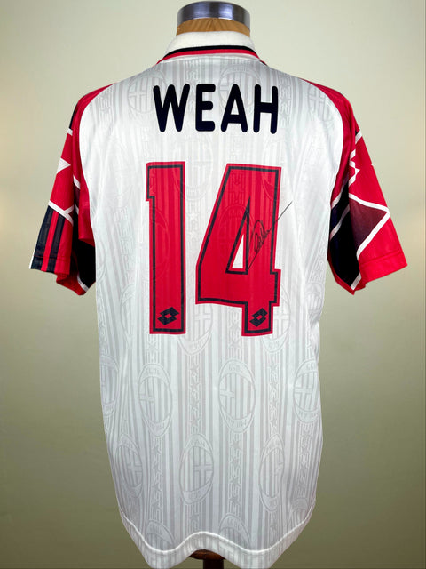 White AC Milan Away jersey with red accents and 'WEAH 14' on a mannequin against a beige background