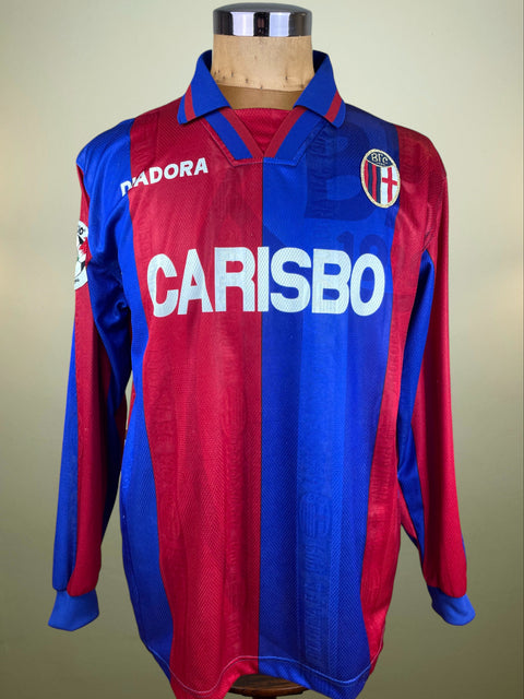 Red and blue Bologna 1996-97 Diadora jersey with Carisbo branding on a mannequin against a beige background