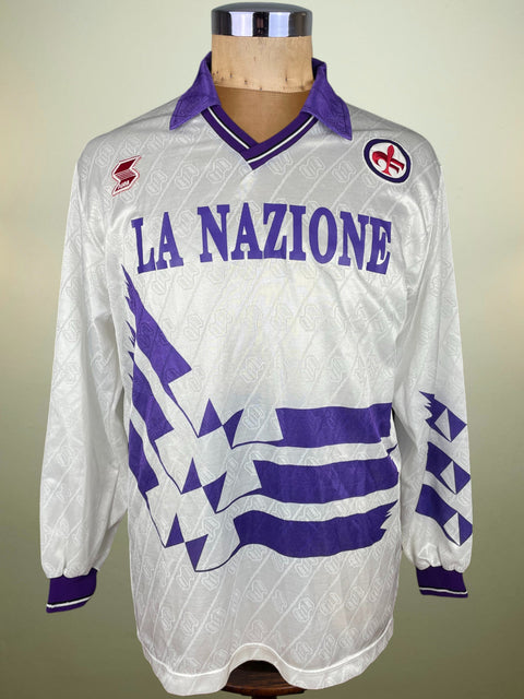 White Fiorentina Away jersey with purple accents and 'La Nazione' text on a mannequin against a neutral background