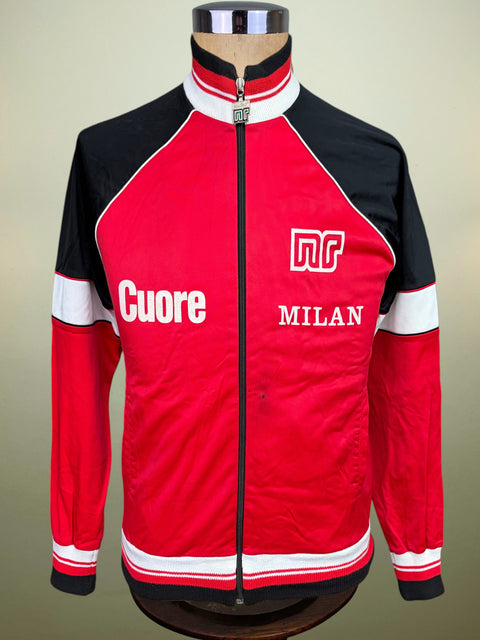 A red, black, and white vintage-style track jacket displayed on a mannequin torso. The jacket features 'Cuore' and 'MILAN' text along with a stylized 'nr' logo on the chest, set against a plain beige background.