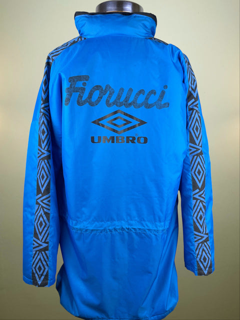 Blue jacket with 'Fiorucci' and 'Umbro' logos on a beige background