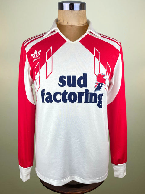 Red and white long-sleeve Bari shirt with 'sud factoring' and Adidas logo on a mannequin against a beige background