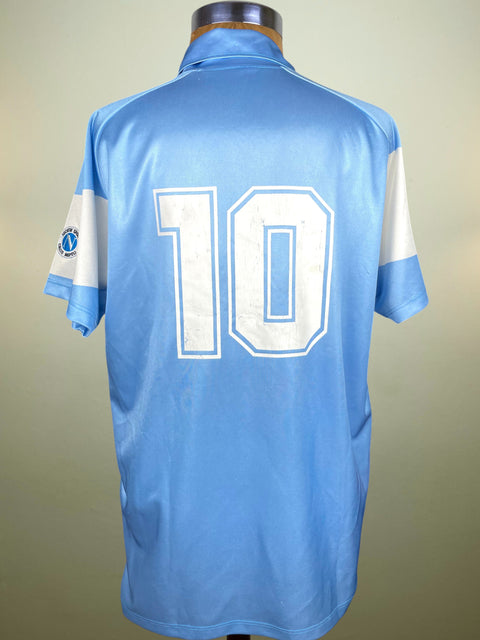 Light blue SSC Napoli 1990 jersey with Diego Maradona's number 10 on a mannequin against a beige background