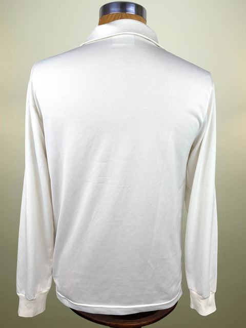 A white long-sleeve collared shirt shown from the back on a wooden dress form mannequin, set against a soft beige gradient background.