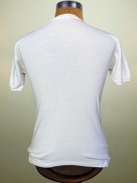 A white short-sleeve t-shirt displayed on a wooden dress form mannequin, viewed from the back against a soft beige background.