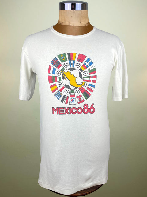 White t-shirt with 'Mexico 86' graphic on a mannequin against a beige background