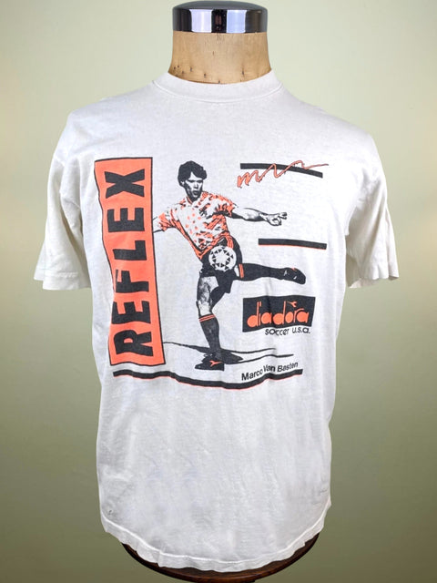 A white short-sleeve Diadora t-shirt displayed on a wooden dress form mannequin. The shirt features a large graphic print on the front with a Marco Van Basten illustration, the word 'REFLEX' in orange inside a vertical orange rectangle, and other black and orange graphic elements.
