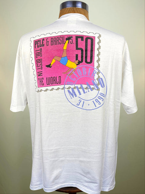 White short-sleeve t-shirt displayed on a mannequin torso, showing the back with a large vintage-style postage stamp graphic in pink, black, yellow, and blue, plus a blue circular stamp design.