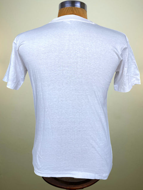 A white short-sleeve crewneck t-shirt displayed on a wooden dress form mannequin, viewed from the back against a light beige gradient background.