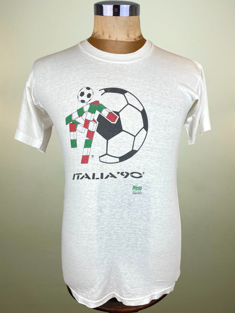 White t-shirt with soccer graphic and 'Italia '90' text on a mannequin against a beige background