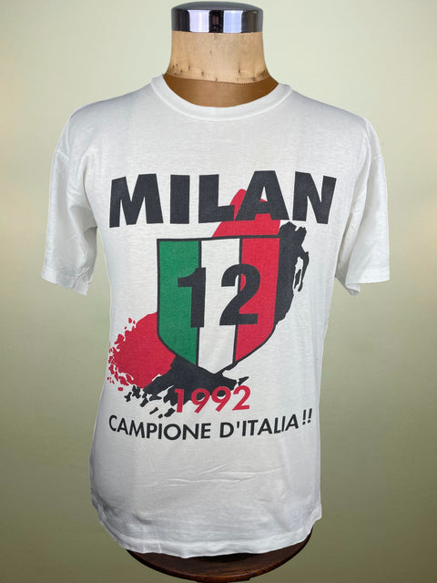 White t-shirt with 'Milan 12 1992 Campione D'Italia' design on a mannequin against a beige background
