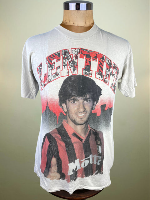 White t-shirt with a graphic of a Lenini wearing a red and black striped shirt on a mannequin against a beige background.