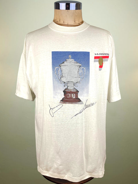 White t-shirt with a graphic of Anglo Italian Cup and Cremonese Logo and text on a mannequin against a plain background