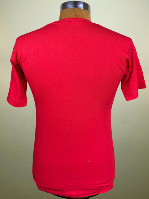 A bright red short-sleeve crewneck t-shirt displayed on a wooden dress form mannequin against a light beige background.