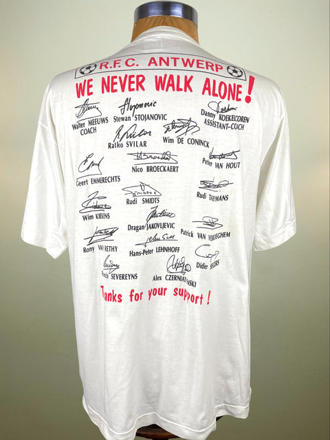 White t-shirt with red and black text and signatures on a mannequin against a neutral background