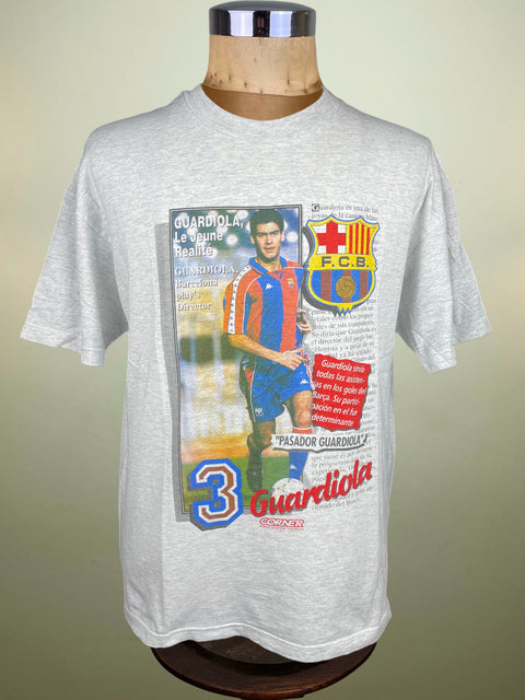 Gray t-shirt with FC Barcelona graphic on a mannequin against a beige background