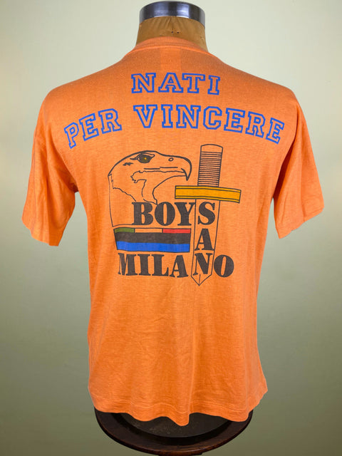 Orange t-shirt with eagle graphic and text saying Nati Per Vincere "Born to Win" on a mannequin against a neutral background