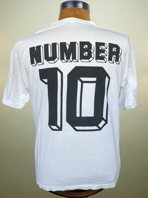 White short-sleeve T-shirt shown from the back on a mannequin torso, featuring large black block lettering that reads 'NUMBER' above a large '10'.