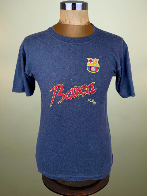 Blue t-shirt with 'Barca' logo on a mannequin against a beige background