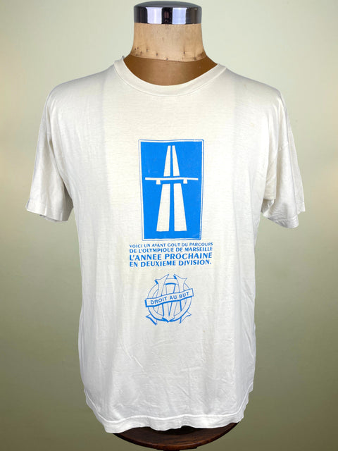 White t-shirt with blue graphic on a mannequin against a beige background