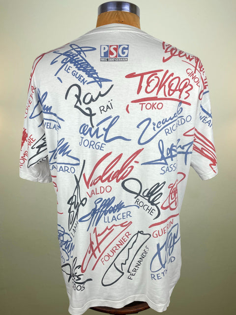 White PSG jersey with various signatures on a mannequin against a plain background