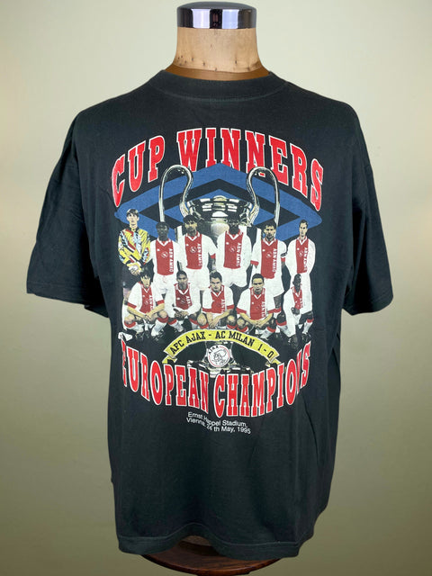 Black t-shirt with sports team graphic and text on a mannequin against a beige background