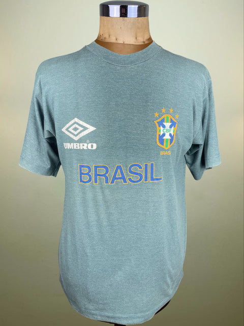 Blue t-shirt with 'Brasil' and Umbro logo on a mannequin against a beige background
