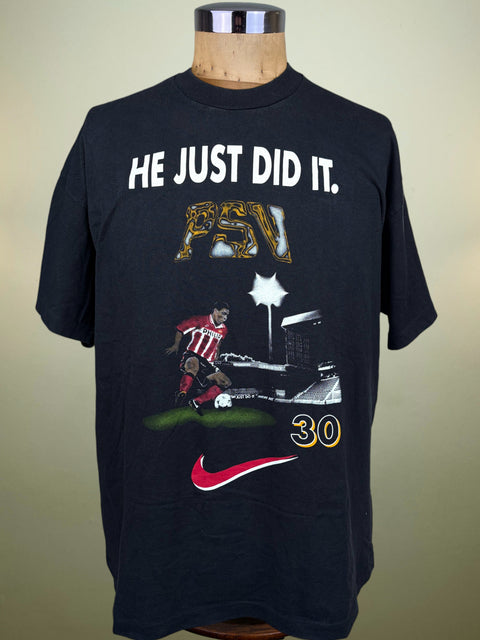 A black Nike t-shirt displayed on a wooden mannequin torso against a beige background. The shirt features a graphic celebrating Ronaldo's 30 Goal Season at PSV with the text 'HE JUST DID IT.