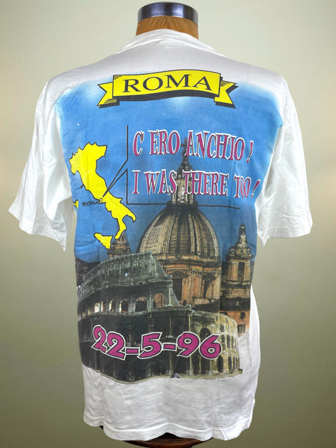 White t-shirt with a colorful graphic design featuring a dome and text on a mannequin against a beige background.