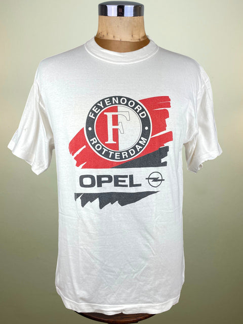 White t-shirt with Opel and Feyenoord Rotterdam logo on a mannequin against a beige background