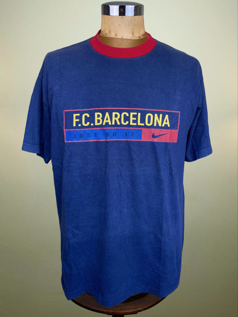 A blue short-sleeve t-shirt with a red collar, featuring a 'F.C Barcelona
