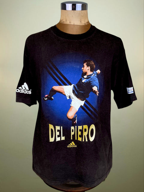 A vintage Adidas short-sleeve graphic t-shirt displayed on a mannequin torso. The black t-shirt features a large graphic of soccer player Del Piero in action, with 'DEL PIERO' printed in yellow text and the Adidas logo on the sleeve and below the graphic.