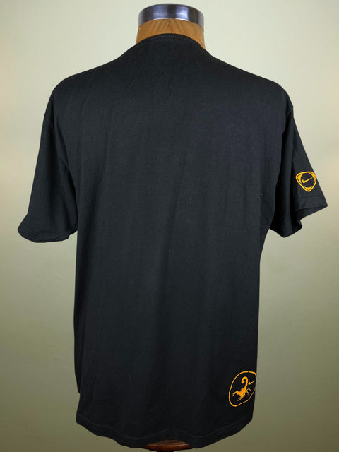 Black Nike Os Tornados t-shirt with yellow Nike logo and small scorpion graphic in the bottom corner on a mannequin against a beige background