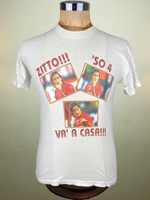 White t-shirt with printed graphics and text on a mannequin against a beige background