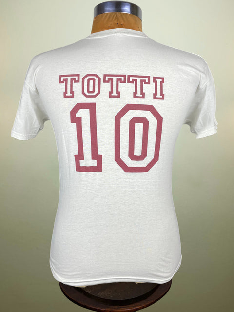 White t-shirt with 'TOTTI 10' printed on the back, displayed on a mannequin against a beige background.