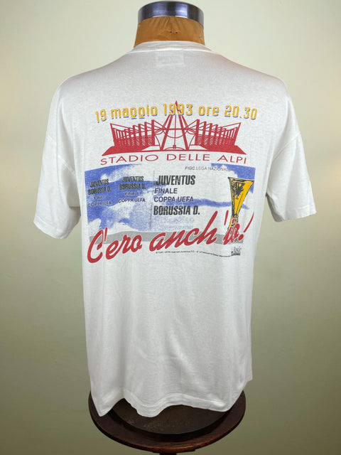 White t-shirt with colorful graphics and text on a mannequin against a beige background
