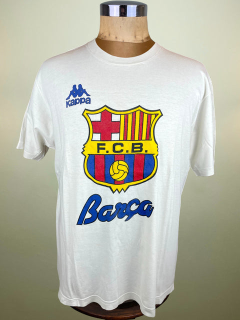 White t-shirt with Barcelona FC logo on a mannequin against a beige background