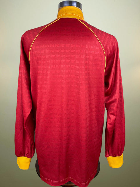 Red AS Roma jersey with yellow accents on a mannequin against a neutral background