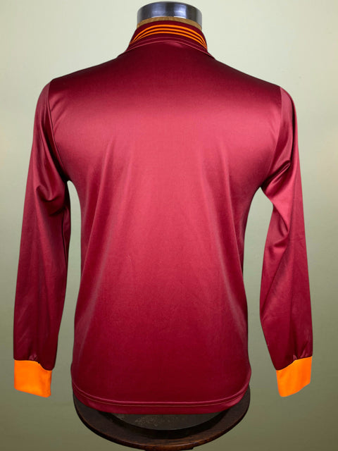 Maroon AS Roma long-sleeve shirt with orange cuffs on a mannequin against a beige background