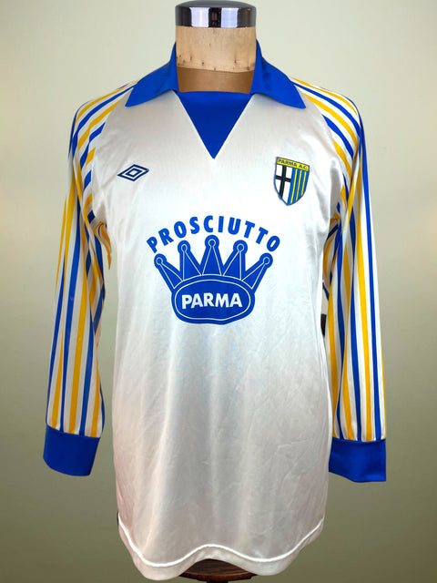 White Parma Calcio jersey with blue and yellow accents on a mannequin against a neutral background and Prosciutto di Parma sponsor across the chest.