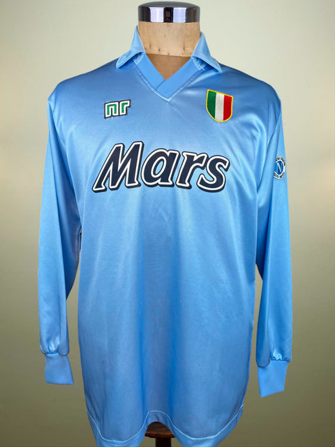 Light blue Napoli 1990-91 jersey made by Ennerre with 'Mars' branding on a mannequin against a beige background