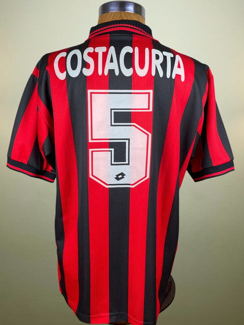 Red and black AC Milan 1997-98 sports jersey with 'Costacurta' and number '5' on a mannequin against a beige background