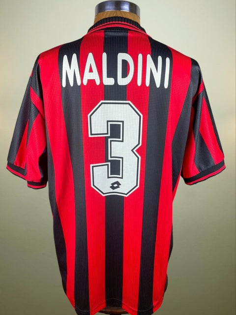 Red and black striped AC Milan 1997-98 sports jersey with 'Maldini' and number '3' on a beige background