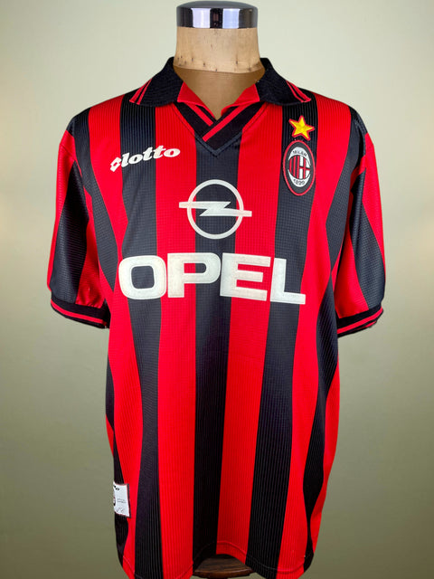 Red and black striped AC Milan 1997-98 Paolo Maldini sports jersey made by Lotto with Opel logo on a mannequin against a beige background