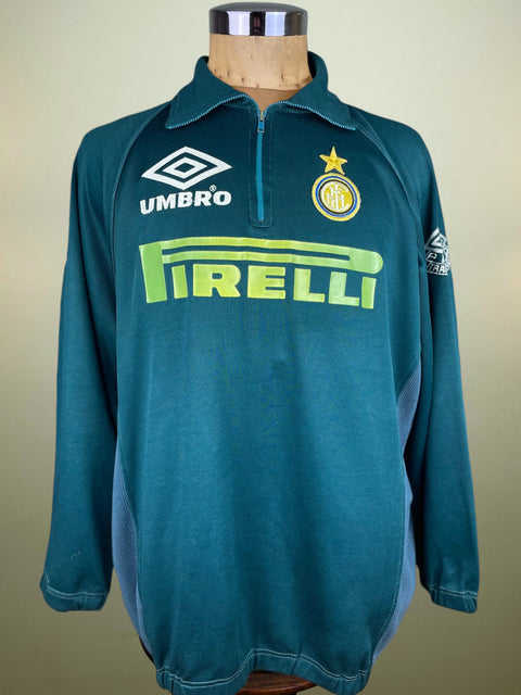 Teal Inter Milan jacket with Umbro and Pirelli logos on a mannequin against a beige background